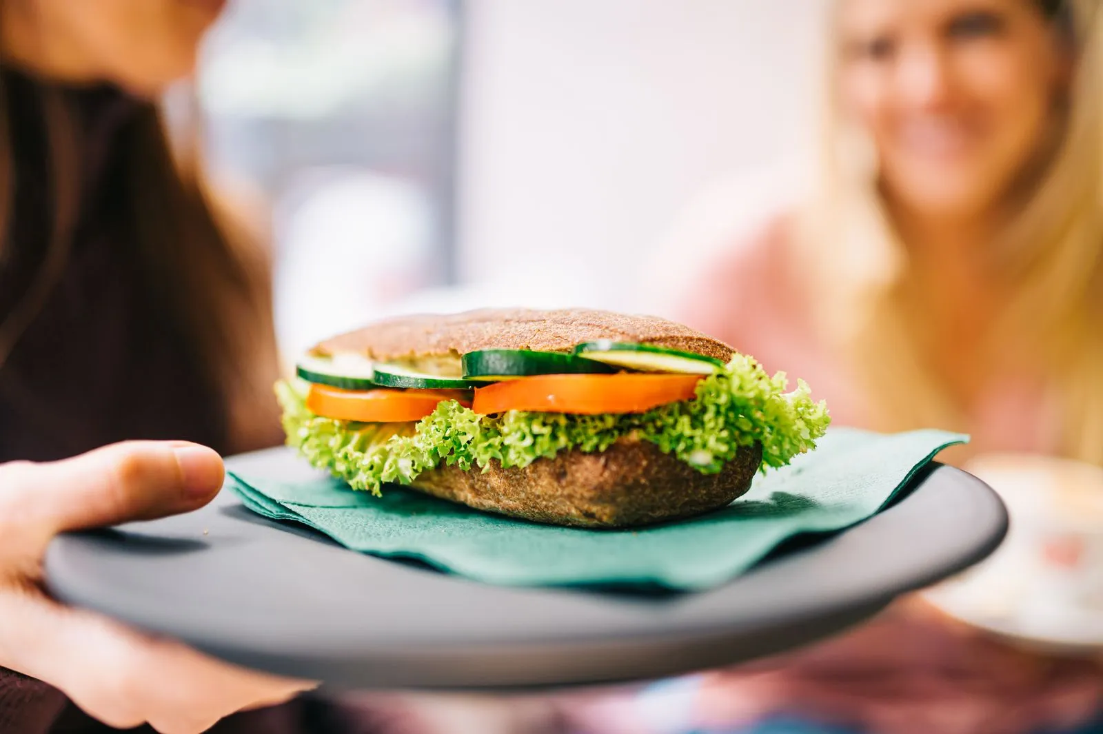 Healthy vegetarian sandwich with cucumbers and tomatoes served on a dark plate.